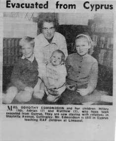 Start of image description, A newspaper clipping from 1963 features an image of Adrian’s mother, Dorothy, sitting on the floor with Adrian, Hilary, and their baby brother, Matthew. Hilary was 10 and Adrian is 7 at the time. Dorothy holds Matthew in her lap. The headline above reads “Evacuated from Cyprus”., end of image description