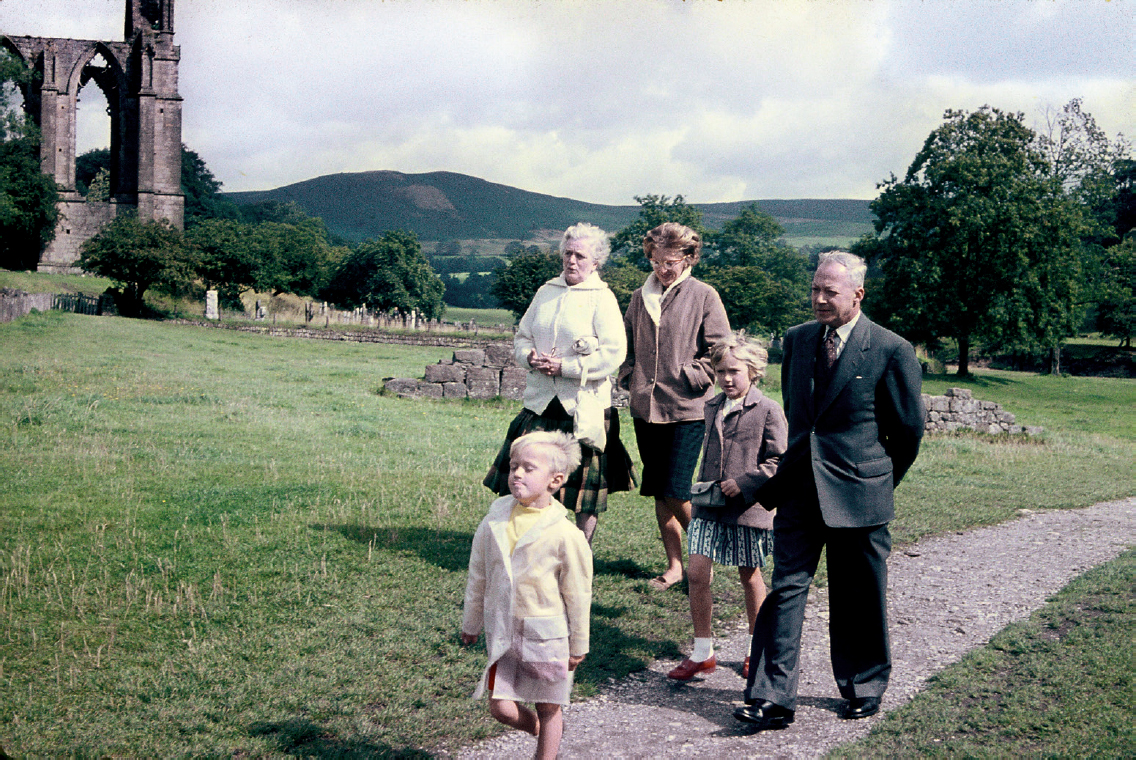 Start of image description, Adrian and family visit Bolton Abbey on an overcast day in 1961. Adrian, aged 4 years old, strides along the path ahead of the other members of the family including Grandma Ed, his mum, his sister Hilary, and Grandad Ed. The family are wearing jackets and raincoats., end of image description